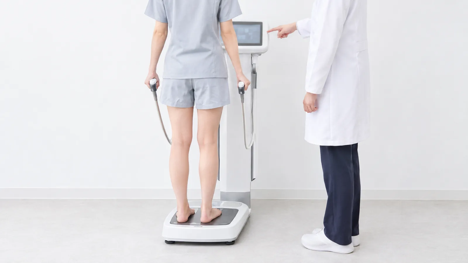 해수원한의원에서 체성분 분석기 위에 서서 한의사의 안내를 받으며 체성분 검사를 받는 모습