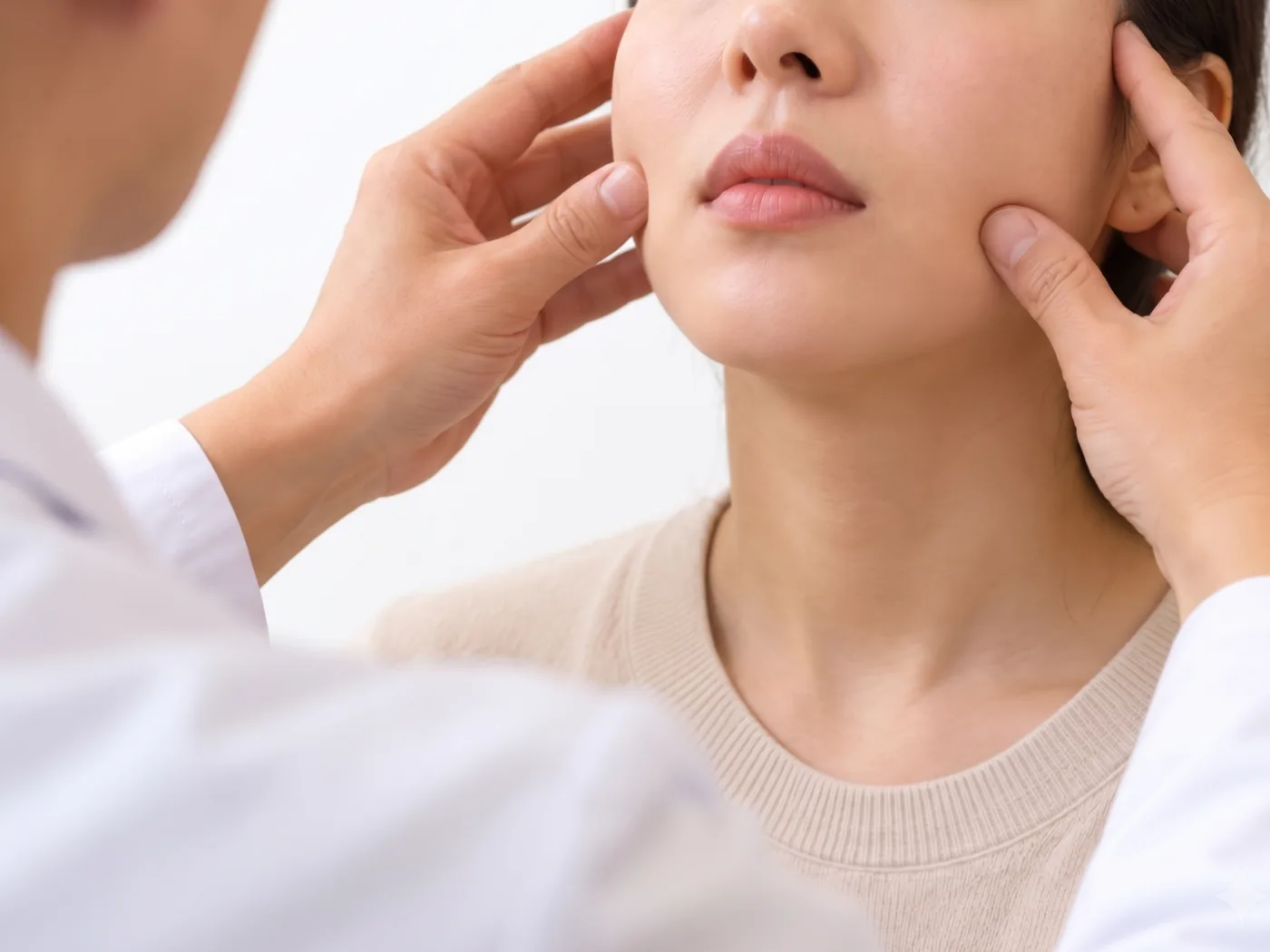 한의사가 양손으로 환자의 양쪽 볼과 관자놀이 근육을 짚어 좌우를 비교하는 장면