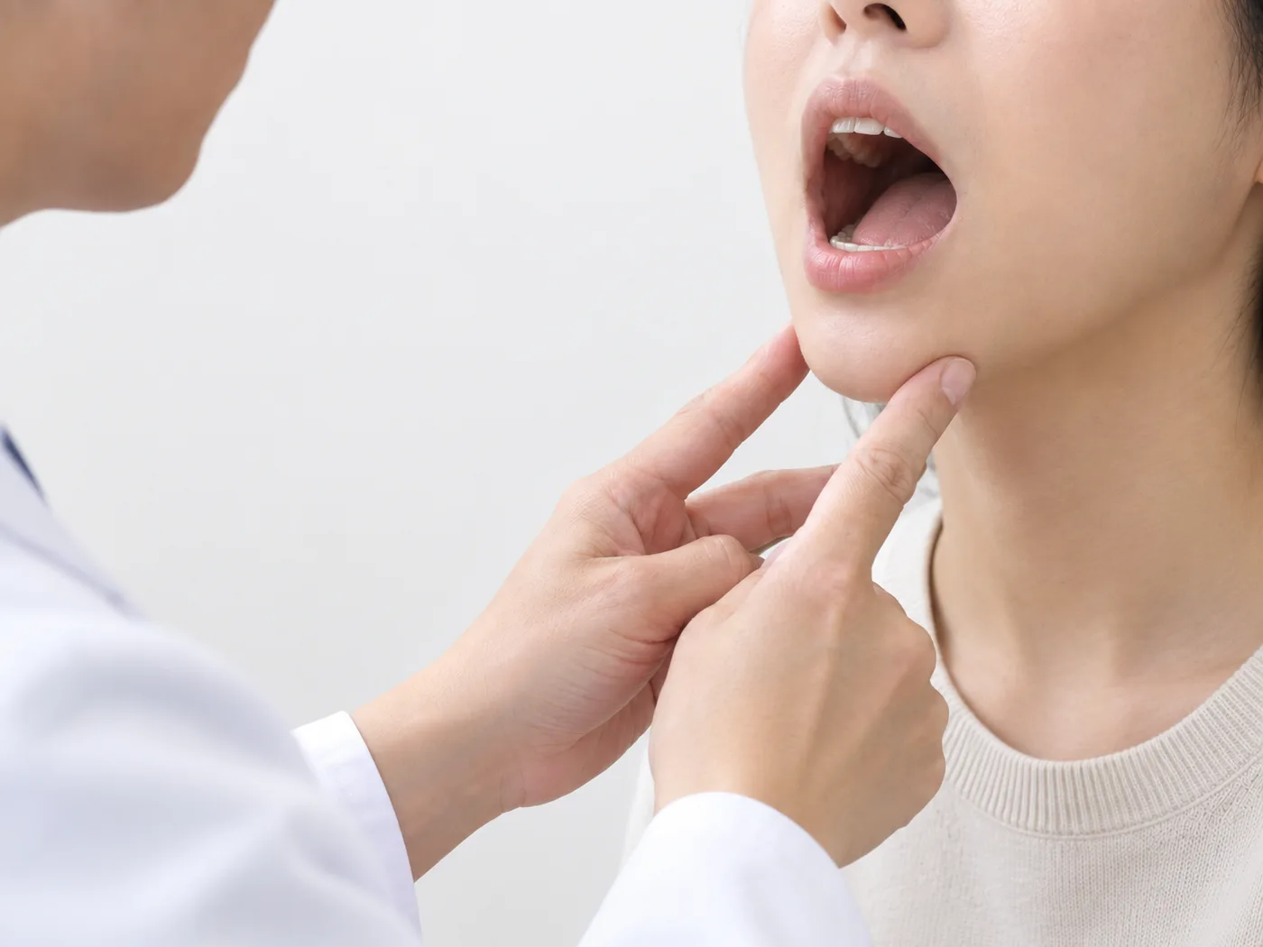 한의사가 손가락으로 환자의 턱 아래를 받쳐 입이 벌어지는 범위를 확인하는 장면